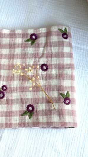 close up video of berry gingham muslin cloth with embroidered flowers